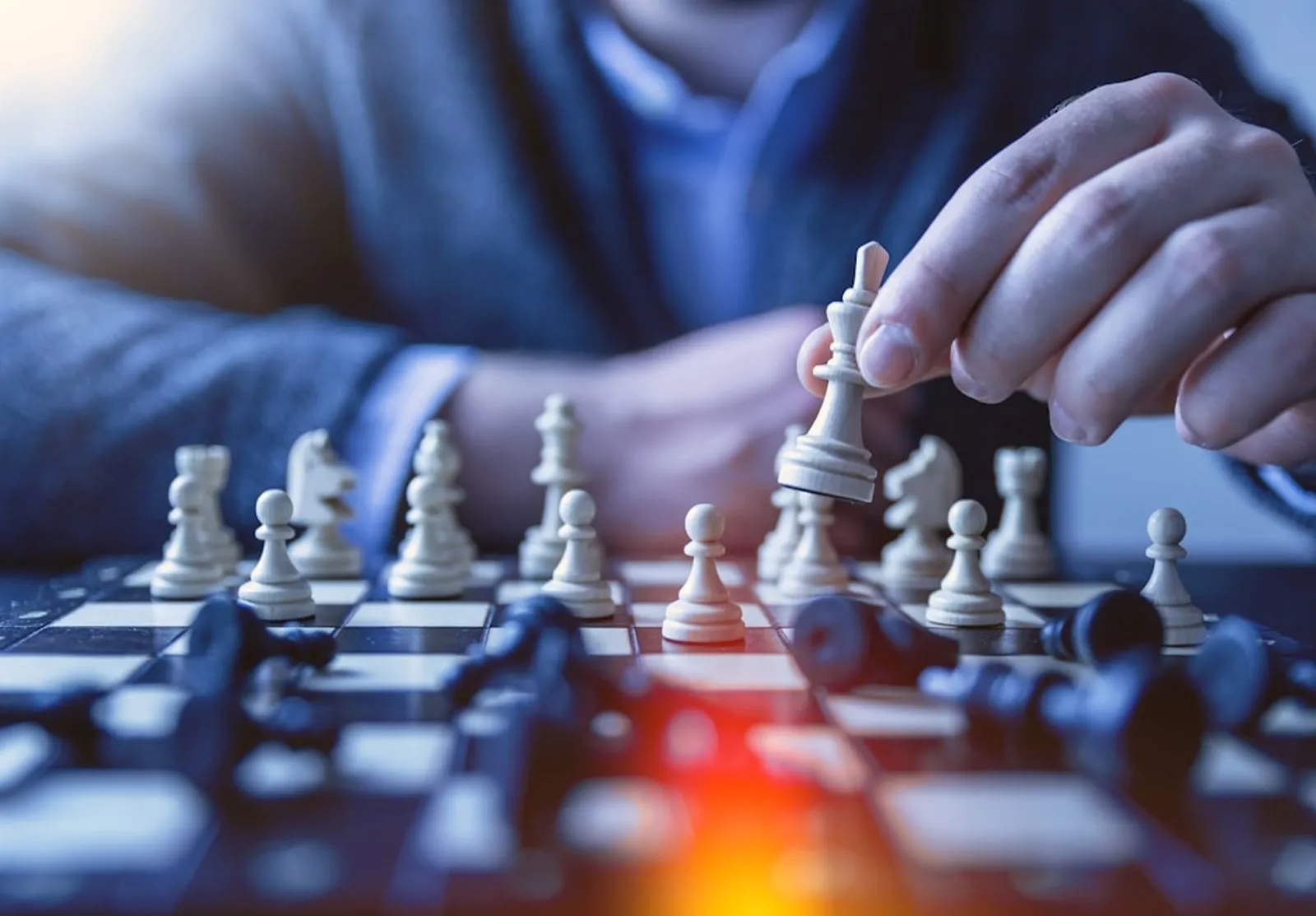 A hand moving a chess piece across the board
