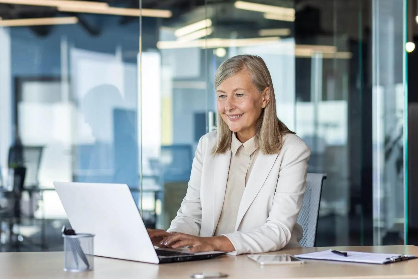 An advisor working at a laptop in a glass-walled office