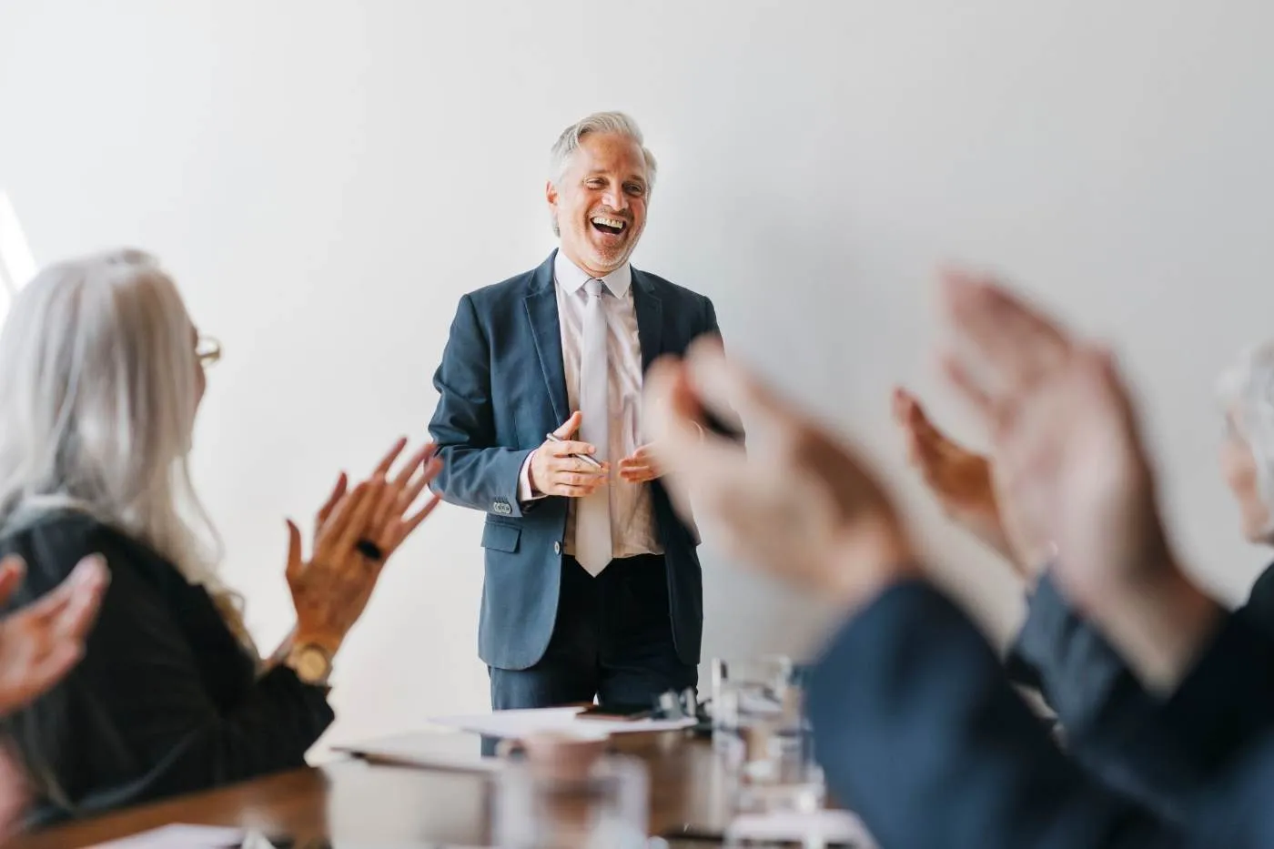 A presenter laughing with a room of applauding advisors