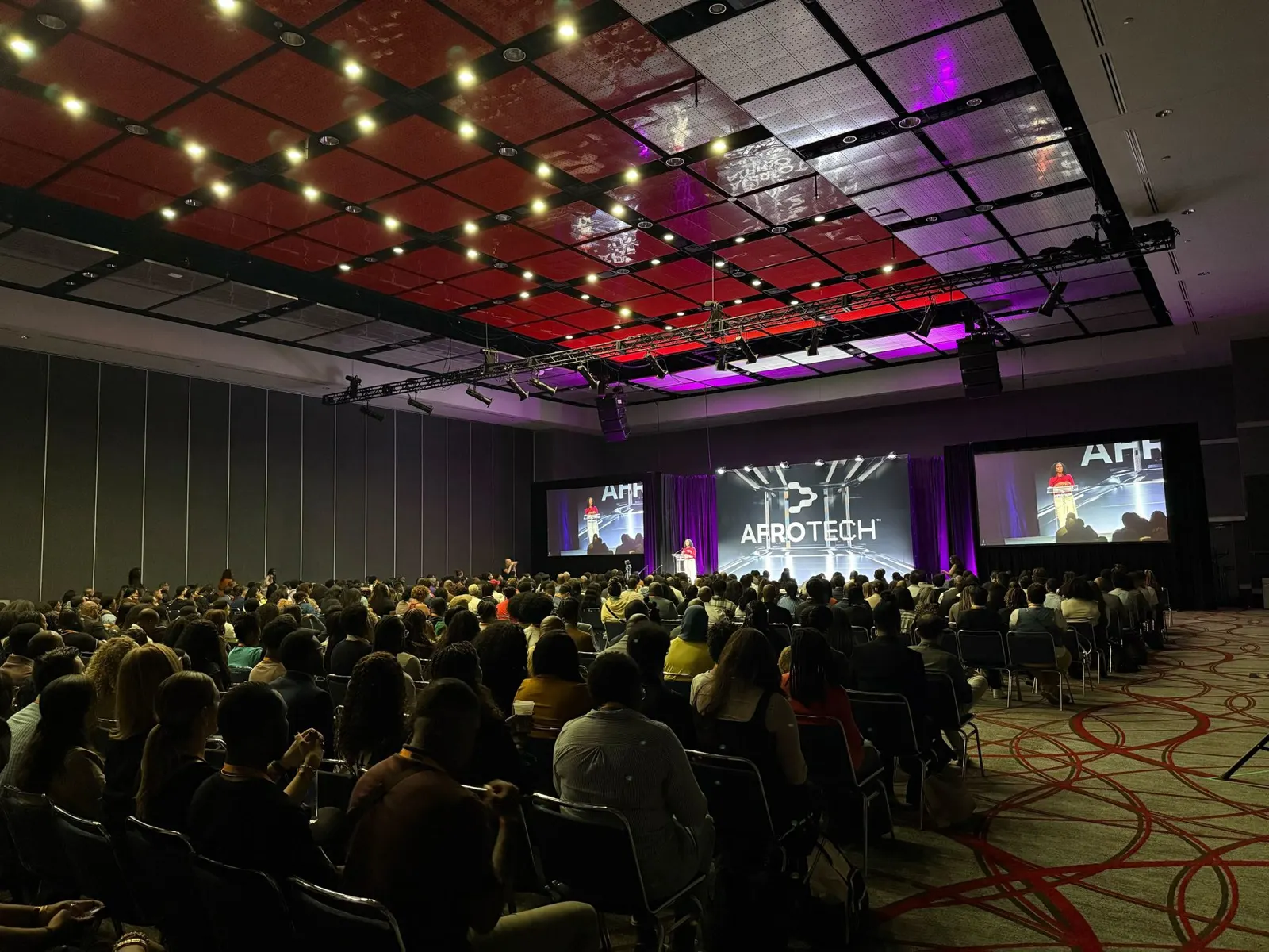 A packed conference hall seen from the back of the room