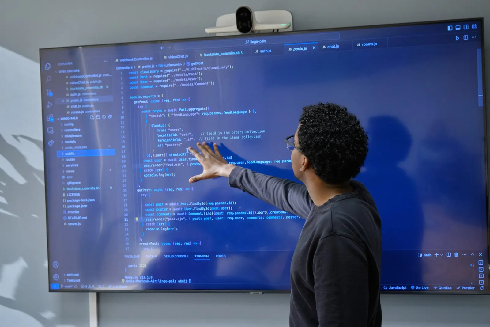 An engineer pointing at code on a large wall display