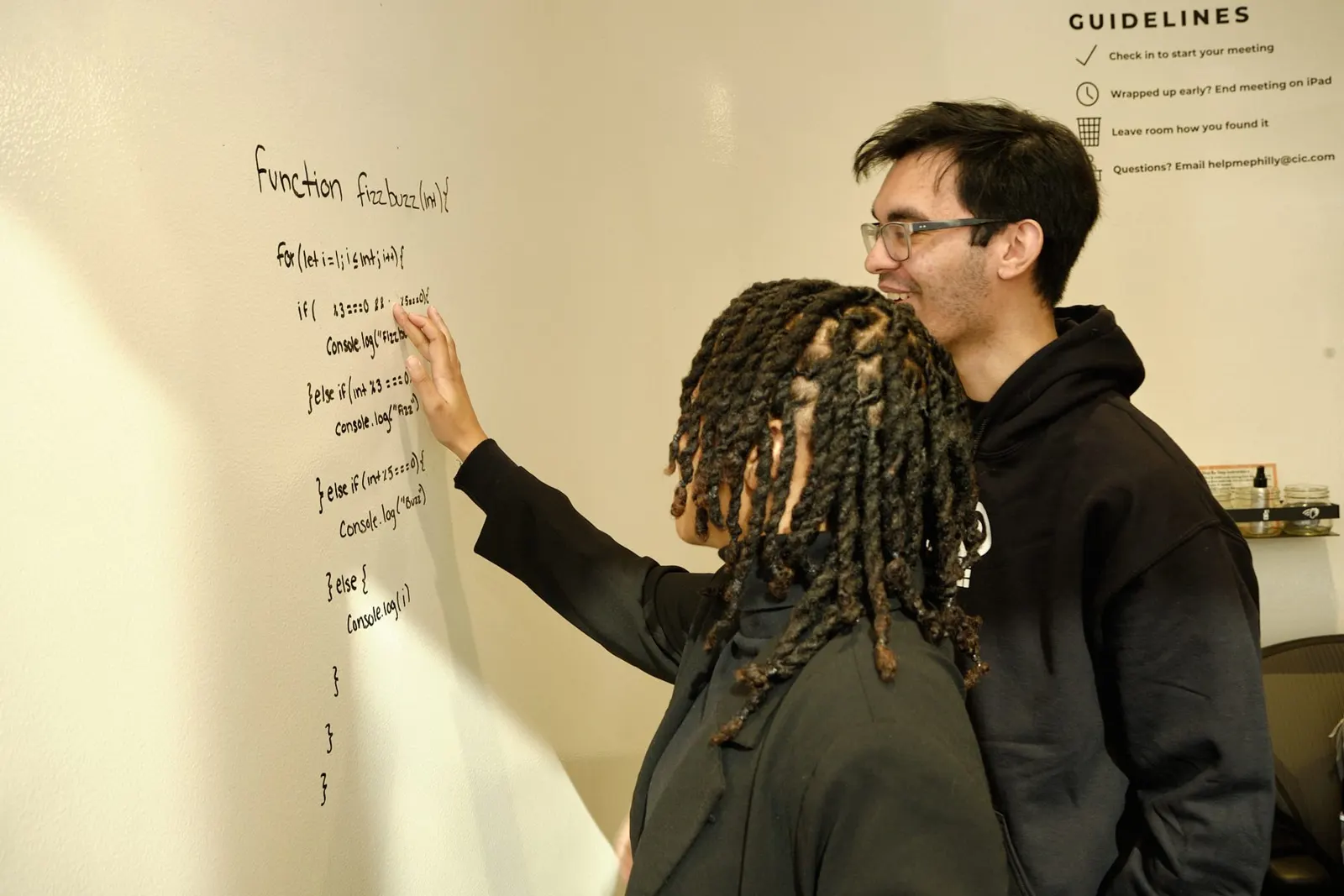 Two engineers working through a problem at a whiteboard